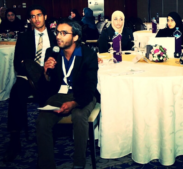 Early photograph of a person speaking into a microphone at an academic event