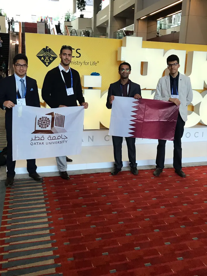 Participants with Qatar University and Qatar flags at the ACS venue.