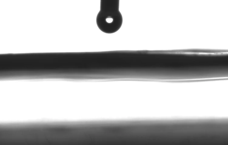 Side-on droplet profile labelled FM2; the image shows a dispenser above a horizontal surface.